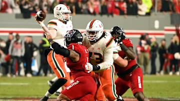 Nov 4, 2023; Raleigh, North Carolina, USA; Miami Hurricanes quarterback Tyler Van Dyke (9) throws a pass as he is pressured by North Carolina State Wolfpack defensive end Davin Vann (1) during the second half at Carter-Finley Stadium.  Mandatory Credit: Rob Kinnan-Imagn Images