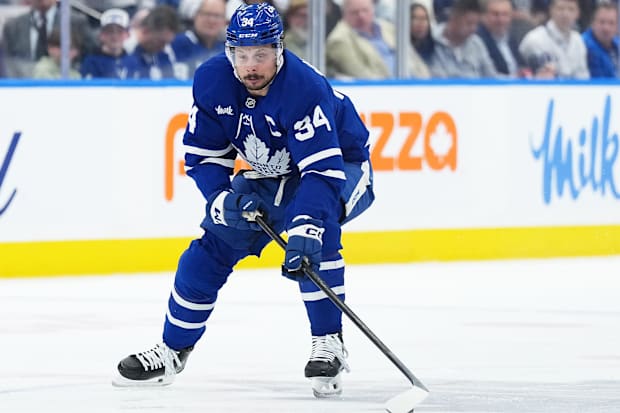 Hockey player in blue uniform skates with the puck