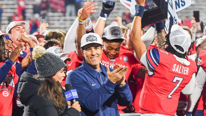 Dec 1, 2023; Lynchburg, VA, USA; Liberty Flames head coach Jamey Chadwell claps as quarterback Kaidon Salter (7) holds the Conference USA championship trophy up after the game against the New Mexico State Aggies at Williams Stadium. Mandatory Credit: Brian Bishop-USA TODAY Sports