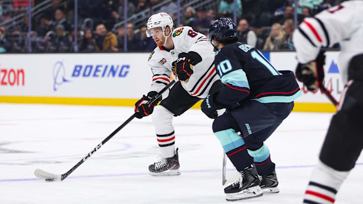 Nov 3, 2025; Seattle, Washington, USA; Chicago Blackhawks defenseman Sam Rinzel (6) passes the puck past Seattle Kraken center Matty Beniers (10) in the first period at Climate Pledge Arena. Mandatory Credit: Kevin Ng-Imagn Images