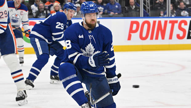 Hockey player in blue uniform blocks shot attempt