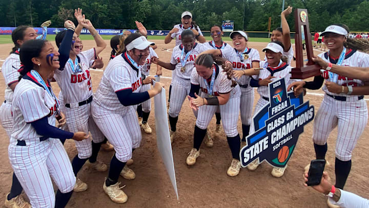 Doral Academy softball players celebrate after being awarded the FHSAA Class 6A state championship trophy on Saturday at Solider’s Creek Park.