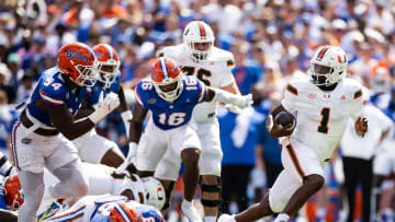 Aug 31, 2024; Gainesville, Florida, USA; Miami Hurricanes quarterback Cam Ward (1) breaks a tackle against Florida Gators defensive lineman Caleb Banks (88) and defensive end Tyreak Sapp (94) during the first half at Ben Hill Griffin Stadium. Mandatory Credit: Matt Pendleton-USA TODAY Sports