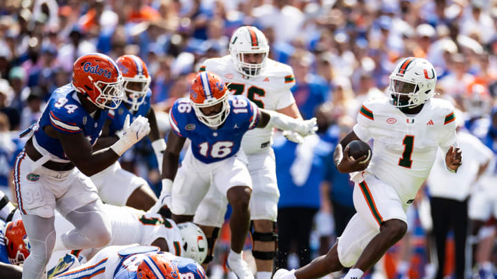 Aug 31, 2024; Gainesville, Florida, USA; Miami Hurricanes quarterback Cam Ward (1) breaks a tackle against Florida Gators defensive lineman Caleb Banks (88) and defensive end Tyreak Sapp (94) during the first half at Ben Hill Griffin Stadium. Mandatory Credit: Matt Pendleton-USA TODAY Sports