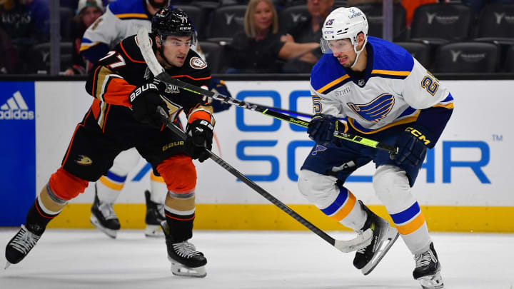 Apr 7, 2024; Anaheim, California, USA; Anaheim Ducks right wing Frank Vatrano (77) plays for the puck against St. Louis Blues center Jordan Kyrou (25) during the third period at Honda Center. Mandatory Credit: Gary A. Vasquez-USA TODAY Sports