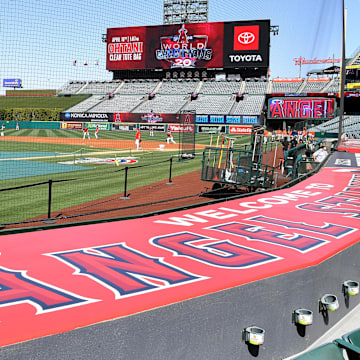 Apr 7, 2022; Anaheim, California, USA;  Workers put finishing touches on the field as players warm up for the opening day game between the Los Angeles Angels and the Houston Astros at Angel Stadium. Mandatory Credit: Jayne Kamin-Oncea-Imagn Images