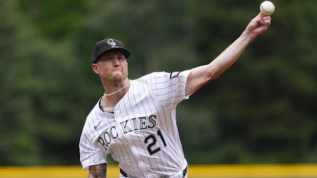 Freeland in a black and white pinstripe uniform releasing a baseball in a black ca