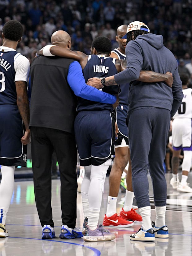 Dallas Mavericks guard Kyrie Irving is helped off the court by forward Naji Marshall (13) and forward Anthony Davis