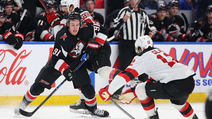 Nov 28, 2025; Buffalo, New York, USA;  Buffalo Sabres right wing Josh Doan (91) plays the puck as New Jersey Devils center Cody Glass (12) defends during the second period at KeyBank Center. Mandatory Credit: Timothy T. Ludwig-Imagn Images