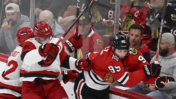 Apr 9, 2026; Chicago, Illinois, USA;  Carolina Hurricanes defenseman Mike Reilly (6) checks Chicago Blackhawks right wing Ilya Mikheyev (95) during the second period at the United Center. Mandatory Credit: Matt Marton-Imagn Images