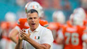 Oct 17, 2025; Miami Gardens, Florida, USA; Miami Hurricanes head coach Mario Cristobal works with his players before the game against the Louisville Cardinals at Hard Rock Stadium. Mandatory Credit: Sam Navarro-Imagn Images