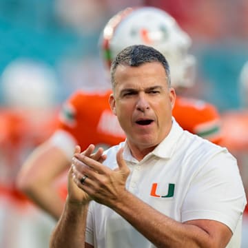 Oct 17, 2025; Miami Gardens, Florida, USA; Miami Hurricanes head coach Mario Cristobal works with his players before the game against the Louisville Cardinals at Hard Rock Stadium. Mandatory Credit: Sam Navarro-Imagn Images