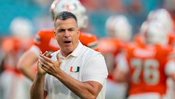 Oct 17, 2025; Miami Gardens, Florida, USA; Miami Hurricanes head coach Mario Cristobal works with his players before the game against the Louisville Cardinals at Hard Rock Stadium. Mandatory Credit: Sam Navarro-Imagn Images