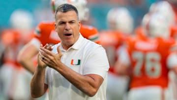 Oct 17, 2025; Miami Gardens, Florida, USA; Miami Hurricanes head coach Mario Cristobal works with his players before the game against the Louisville Cardinals at Hard Rock Stadium.