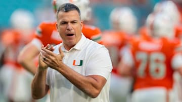 Oct 17, 2025; Miami Gardens, Florida, USA; Miami Hurricanes head coach Mario Cristobal works with his players before the game against the Louisville Cardinals at Hard Rock Stadium. Mandatory Credit: Sam Navarro-Imagn Images