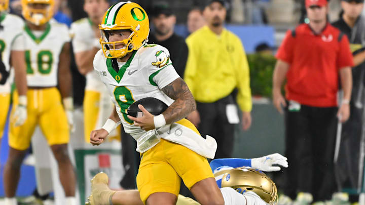 Sep 28, 2024; Pasadena, California, USA; Oregon Ducks quarterback Dillon Gabriel (8) runs past UCLA Bruins linebacker Carson Schwesinger (49) during the second quarter at Rose Bowl. Mandatory Credit: Robert Hanashiro-Imagn Images