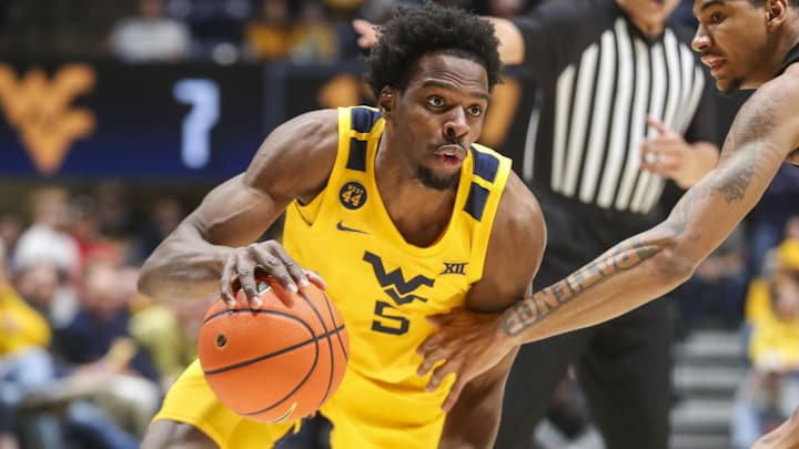 Feb 19, 2025; Morgantown, West Virginia, USA; West Virginia Mountaineers guard Toby Okani (5) dribbles against Cincinnati Bearcats forward Dillon Mitchell (23) during the first half at WVU Coliseum. Mandatory Credit: Ben Queen-Imagn Images