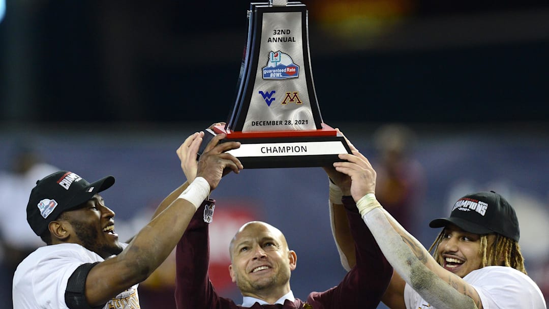 Dec 28, 2021; Phoenix, AZ, USA; Minnesota Golden Gophers head coach P. J. Fleck (center) celebrates with the trophy alongside players Tyler Nubin (left) and Ky Thomas (right) after defeating the West Virginia Mountaineers at Chase Field. Mandatory Credit: Joe Camporeale-Imagn Images Dec 28, 2021; Phoenix, AZ, USA; Minnesota Golden Gophers head coach P. J. Fleck (center) celebrates with the trophy alongside players Tyler Nubin (left) and Ky Thomas (right) after defeating the West Virginia Mountaineers at Chase Field. Mandatory Credit: Joe Camporeale-Imagn Images