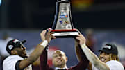 Dec 28, 2021; Phoenix, AZ, USA; Minnesota Golden Gophers head coach P. J. Fleck (center) celebrates with the trophy alongside players Tyler Nubin (left) and Ky Thomas (right) after defeating the West Virginia Mountaineers at Chase Field. Mandatory Credit: Joe Camporeale-Imagn Images
