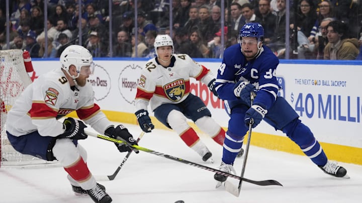 Apr 2, 2025; Toronto, Ontario, CAN; Toronto Maple Leafs forward Auston Matthews (34) passes the puck as Florida Panthers forward Sam Bennett (9) and defenseman Gustav Forsling (42) close in during the first period at Scotiabank Arena. Mandatory Credit: John E. Sokolowski-Imagn Images
