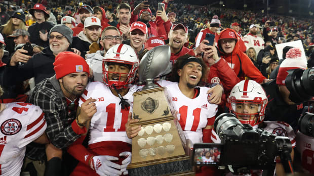 Nebraska Cornhuskers quarterback Casey Thompson and defensive back Braxton Clark hold the Heroes Trophy with fans.