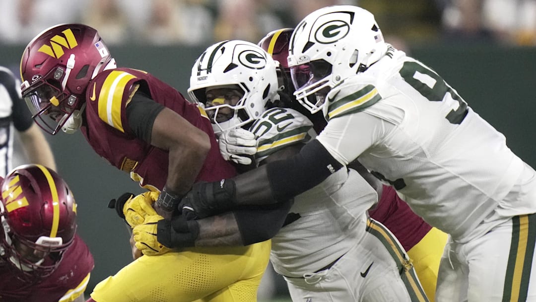 Sep 11, 2025; Green Bay, Wisconsin, USA; Washington Commanders quarterback Jayden Daniels (5) is sacked by Green Bay Packers defensive end Rashan Gary (52) and defensive tackle Devonte Wyatt (95) during the third quarter at Lambeau Field.