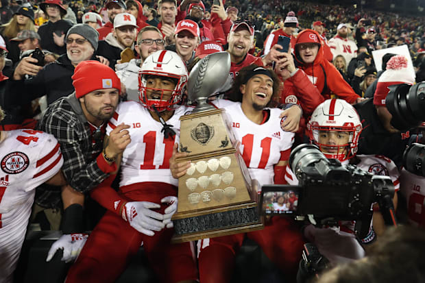 Nebraska Cornhuskers quarterback Casey Thompson (11) and defensive back Braxton Clark (11) hold the Heroes Trophy with fans.
