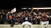 Nov 29, 2025; Charlottesville, Virginia, USA; Virginia Cavaliers tight end Tekai Kirby (81) and Cavaliers wide receiver Trell Harris (11) leap onto the wall in the student sections to celebrate with students and fans after their game against the Virginia Tech Hokies at Scott Stadium. Mandatory Credit: Geoff Burke-Imagn Images