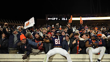 Nov 29, 2025; Charlottesville, Virginia, USA; Virginia Cavaliers tight end Tekai Kirby (81) and Cavaliers wide receiver Trell Harris (11) leap onto the wall in the student sections to celebrate with students and fans after their game against the Virginia Tech Hokies at Scott Stadium. Mandatory Credit: Geoff Burke-Imagn Images