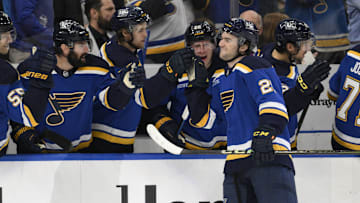 Apr 15, 2025; St. Louis, Missouri, USA; St. Louis Blues right wing Jimmy Snuggerud (21) is congratulated by teammates after scoring his first NHL goal against the Utah Hockey Club during the first period at Enterprise Center. Mandatory Credit: Jeff Le-Imagn Images