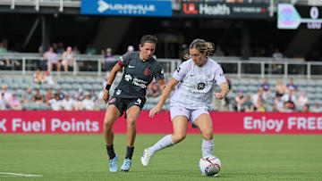 Jun 29, 2024; Louisville, Kentucky, USA;  Racing Louisville FC midfielder Jordan Baggett (right) maneuvers the ball past Bay FC defender Emily Menges (left) during the second half at Lynn Family Stadium. Mandatory Credit: EM Dash-Imagn Images