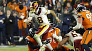 Nov 30, 2025; Landover, Maryland, USA; Washington Commanders quarterback Marcus Mariota (8) runs with the ball as Denver Broncos defensive end John Franklin-Myers (98) and Broncos linebacker Nik Bonitto (15) attempt a tackle during overtime at Northwest Stadium. Mandatory Credit: Geoff Burke-Imagn Images