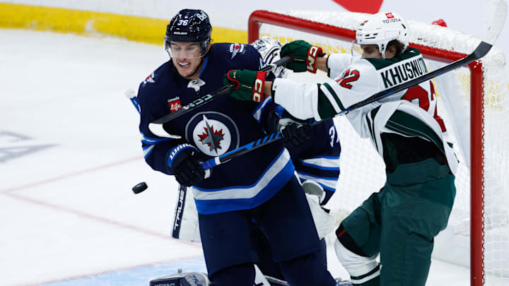 Dec 21, 2024; Winnipeg, Manitoba, CAN;  Winnipeg Jets forward Morgan Barron (36) battles for position with Minnesota Wild forward Marat Khusnutdinov (22) during the third period at Canada Life Centre. Mandatory Credit: Terrence Lee-Imagn Images