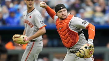 Sep 22, 2024; Kansas City, Missouri, USA; San Francisco Giants catcher Patrick Bailey (14) throws to first base as relief pitcher Sean Hjelle (64) looks on during the eighth inning against the Kansas City Royals at Kauffman Stadium. Jay Biggerstaff-Imagn Images