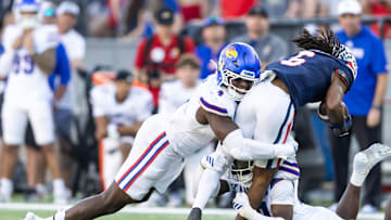 Nov 8, 2025; Tucson, Arizona, USA; Kansas Jayhawks linebacker Trey Lathan (4) tackles Arizona Wildcats wide receiver Javin Whatley (6) at Arizona Stadium. Mandatory Credit: Mark J. Rebilas-Imagn Images
