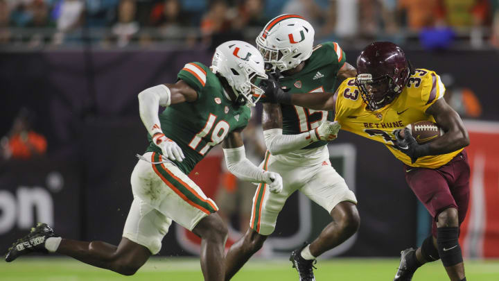 Sep 14, 2023; Miami Gardens, Florida, USA; Bethune Cookman Wildcats running back Jaiden Bivens (33) runs with the football ahead of Miami Hurricanes defensive back Markeith Williams (15) and defensive back Jaden Harris (19) during the third quarter at Hard Rock Stadium. Mandatory Credit: Sam Navarro-USA TODAY Sports