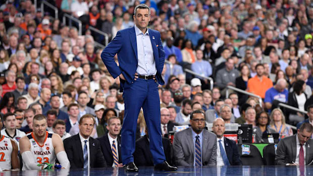 Virginia men's basketball coach stands on the sidelines with his hands on his hips during a game.