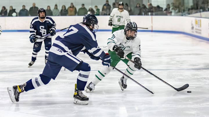 Aidan Cruz (21) of Dartmouth High School moves the puck into the Somerset Berkley end of the ice while Steven Erickson (7) of Somerset Berkley forechecks on the play.
