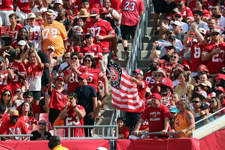 San Francisco 49ers fans cheer and hold up an American flag against the Tampa Bay Buccaneers.