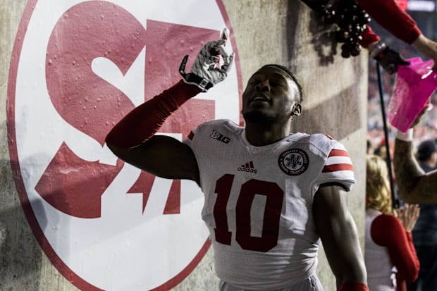 Nebraska Cornhuskers cornerback Joshua Kalu (10) points skyward after touching the sign honoring punter Sam Foltz (27).