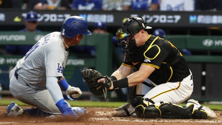 Pittsburgh Pirates catcher Henry Davis (32) tags Los Angeles Dodgers second baseman Miguel Rojas (11) out at home plate attempting to score during the fifth inning at PNC Park. 