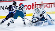 Feb 24, 2025; Winnipeg, Manitoba, CAN;  San Jose Sharks defenseman Shakir Muhamadullin (85) checks Winnipeg Jets forward Rasmus Kupari (15) in front of San Jose Sharks goalie Vitek Vanecek (41) during the third period at Canada Life Centre. Mandatory Credit: Terrence Lee-Imagn Images