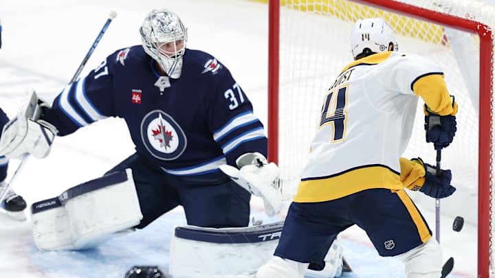 Jan 7, 2025; Winnipeg, Manitoba, CAN; Nashville Predators center Gustav Nyquist (14) tries to control a rebound on Winnipeg Jets goaltender Connor Hellebuyck (37) in the third period at Canada Life Centre. Mandatory Credit: James Carey Lauder-Imagn Images