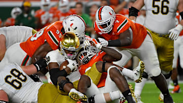 Nov 11, 2017; Miami Gardens, FL, USA; Miami Hurricanes defensive lineman Chad Thomas (9) and defensive lineman Joe Jackson (99) and defensive lineman Kendrick Norton (7) bring down Notre Dame Fighting Irish running back Josh Adams (33) during the first half at Hard Rock Stadium. Mandatory Credit: Jasen Vinlove-Imagn Images