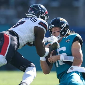 Dec 1, 2024; Jacksonville, Florida, USA; Jacksonville Jaguars quarterback Trevor Lawrence (16) slides down in front of Houston Texans linebacker Azeez Al-Shaair (0) in the second quarter in the second quarter at EverBank Stadium. Mandatory Credit: Nathan Ray Seebeck-Imagn Images
