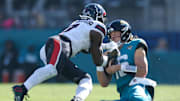 Dec 1, 2024; Jacksonville, Florida, USA; Jacksonville Jaguars quarterback Trevor Lawrence (16) slides down in front of Houston Texans linebacker Azeez Al-Shaair (0) in the second quarter in the second quarter at EverBank Stadium. Mandatory Credit: Nathan Ray Seebeck-Imagn Images