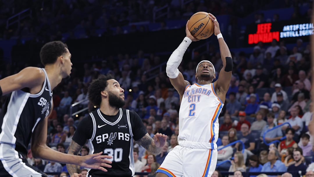Dec 25, 2025; Oklahoma City, Oklahoma, USA; Oklahoma City Thunder guard Shai Gilgeous-Alexander (2) shoots beside San Antonio Spurs forward Julian Champagnie (30) during the second half at Paycom Center. Mandatory Credit: Alonzo Adams-Imagn Images