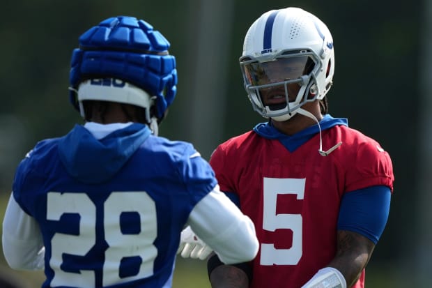 Football players Anthony Richardson and Jonathan Taylor high five at practice wearing red and blue jerseys.