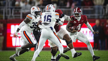 Nov 30, 2024; Tuscaloosa, Alabama, USA; Alabama Crimson Tide quarterback Jalen Milroe (4) runs the ball against Auburn Tigers nose tackle Jalen McLeod (35) and linebacker Demarcus Riddick (16) during the fourth quarter at Bryant-Denny Stadium. Mandatory Credit: Will McLelland-Imagn Images