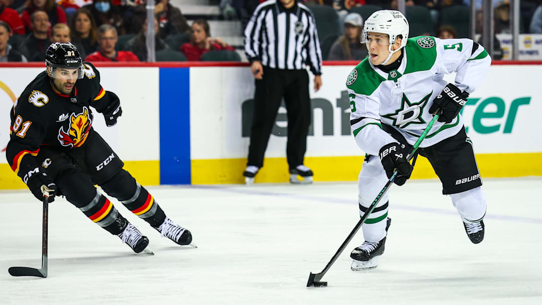 Mar 3, 2026; Calgary, Alberta, CAN; Dallas Stars defenseman Nils Lundkvist (5) controls the puck in front of Calgary Flames center Nazem Kadri (91) during the third period at Scotiabank Saddledome. Mandatory Credit: Sergei Belski-Imagn Images
